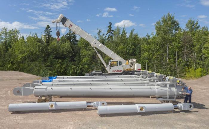 Large bore, long stroke custom hydraulic cylinders with triple redundant transducers, eight end-of-stroke switches each, and internal dogging mechanism in yard in front of crane.